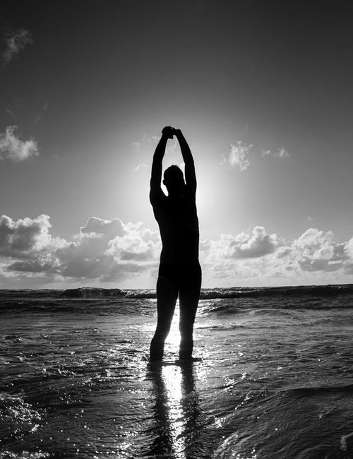 Silhouette of a man stretching against a sunrise, symbolizing well-being.